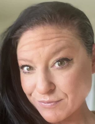 Portrait of a middle-aged woman with dark hair pulled back, smiling at the camera against a neutral background